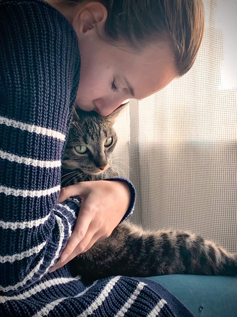 A woman hugs her beloved tabby cat. Image is for illustrative purposes only. Photo by Remy Gieling on Unsplash